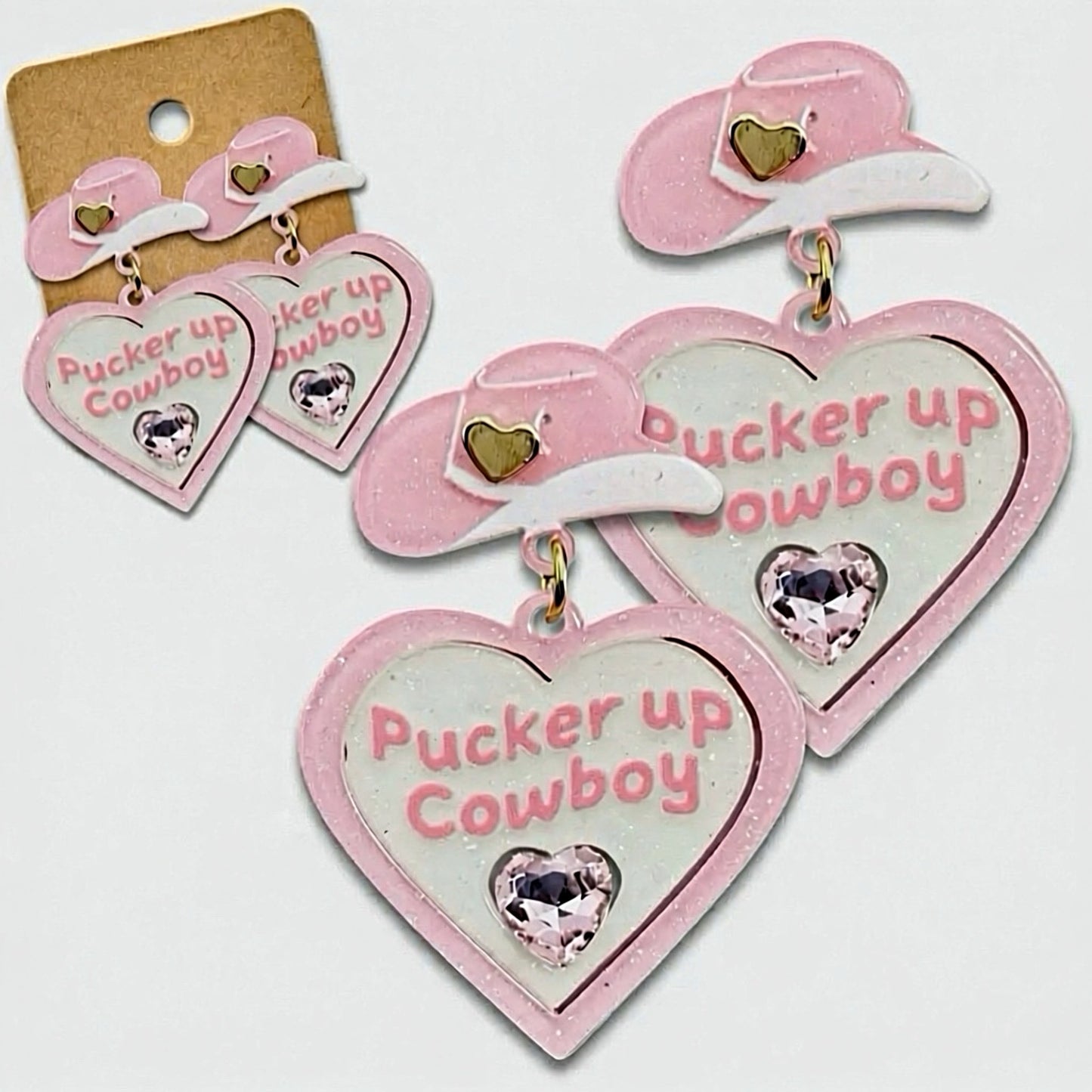 Still hearts and turn heads with the Pucker Up Cowboy earrings y’all! These statement earrings feature sweet pink cowboy hats paired with heart shaped drops stamped with Pucker Up Cowboy and finished with a touch of sparkle. Fun, flirty and full of western charm they’re the perfect accessory for adding personality to your outfit.
Made in the USA
Length: 2”