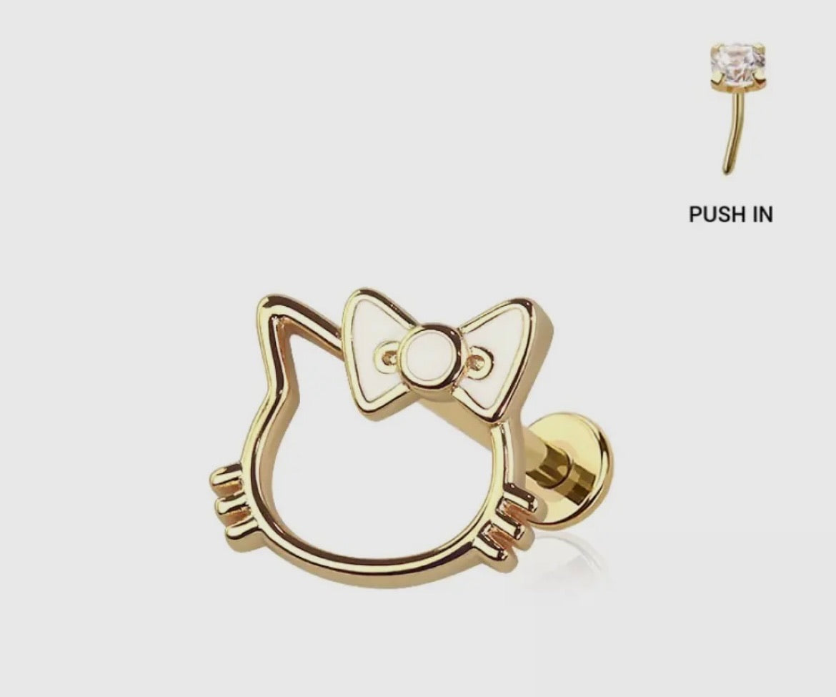 Sweet, iconic and instantly recognizable. Featuring a sleek kitty silhouette finished with a dainty bow bringing playful nostalgic charm with a modern wearable edge. It’s cute, flirty and made for babes who love a little throwback style mixed with underground cool. Available in silver or gold.

Hidden inside SSB Underground this exclusive labret ring is a nod to classic cute girl vibes with a grown up twist.

 Gold 